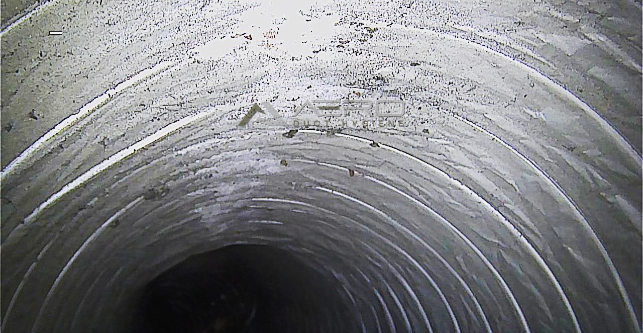 Inside a flexible supply duct, with dust and debris settled along the top of the run