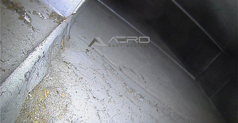 Debris settled along the base of a main supply duct